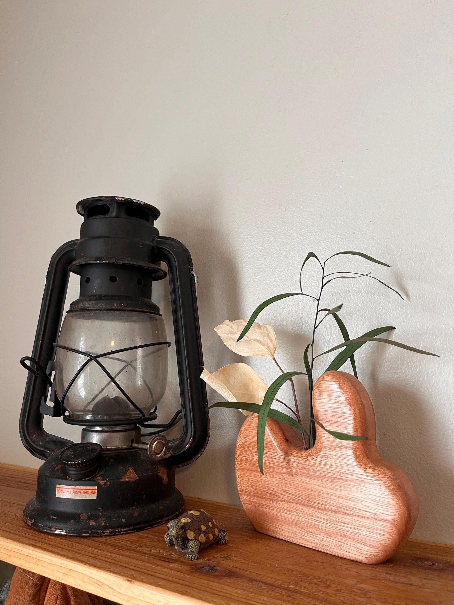 Vintage-style lantern on a wooden surface with a plant and small turtle figurine.