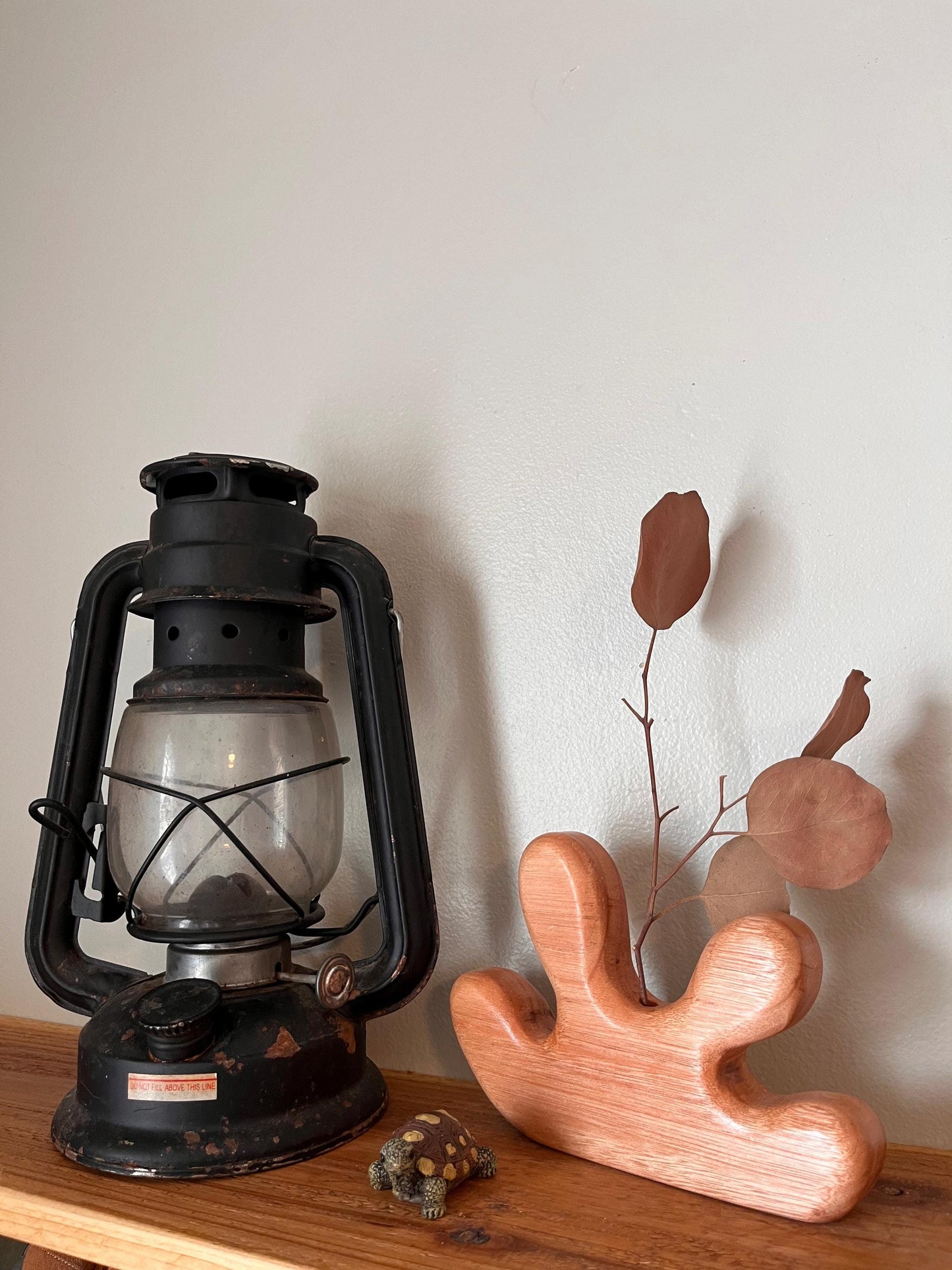 Vintage-style lantern and wooden sculpture on a wooden surface with a neutral background